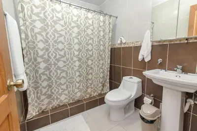 a bathroom with a toilet and a shower curtain at Spacious 3BR APMT- smart speakers Airport transfer in Sosúa