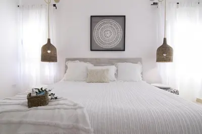 a white bedroom with a large white bed with white pillows at New Beachfront Penthouse in Las Terrenas