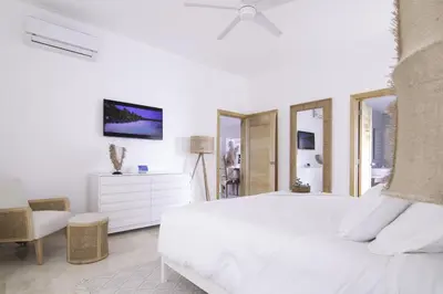 a white bedroom with a bed and a chair at New Beachfront Penthouse in Las Terrenas