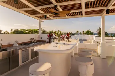 an outdoor kitchen with a large island and stools at New Beachfront Penthouse in Las Terrenas
