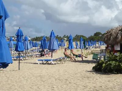 a group of chairs and umbrellas on a beach at CortLang Vacation Rentals, El Pueblito in San Felipe de Puerto Plata