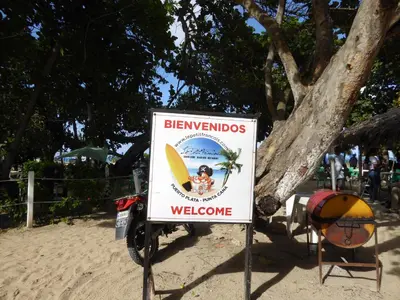 a sign on the beach with a yellow surfboard at CortLang Vacation Rentals, El Pueblito in San Felipe de Puerto Plata