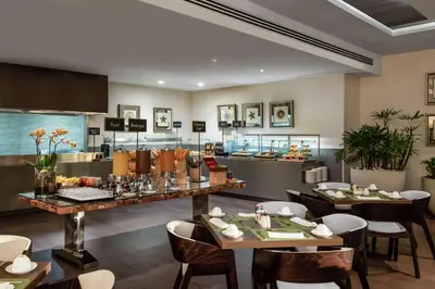 a restaurant with tables and chairs and a kitchen at Embassy Suites by Hilton Santo Domingo in Santo Domingo