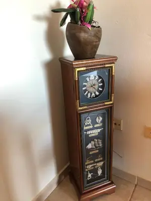 a grandfather clock with a vase on top of it at Agualina Kite Hotel Oceanfront Apartments in Cabarete