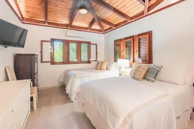 a bedroom with two beds and a flat screen tv at Fun in the sun classic villa at Los Lagos in Casa de Campo in Cajuiles