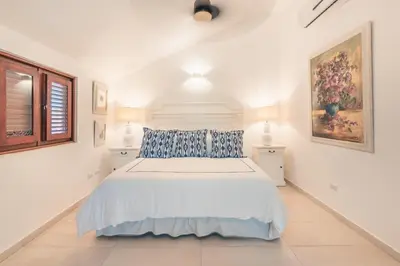 a white bedroom with a large bed with blue pillows at Fun in the sun classic villa at Los Lagos in Casa de Campo in Cajuiles