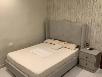 a small bedroom with a bed and a nightstand at Hotel Blue Malecón And Spa in Santo Domingo