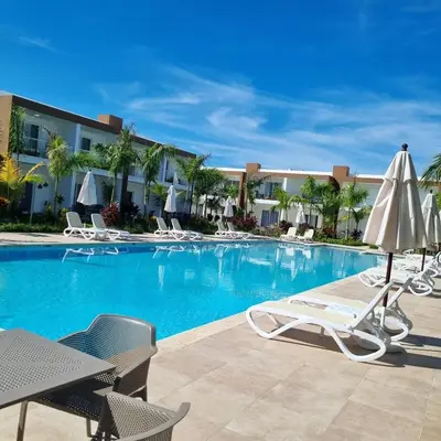 a swimming pool with lounge chairs and an umbrella at Hermosa townhouse boca paraíso in Boca Chica