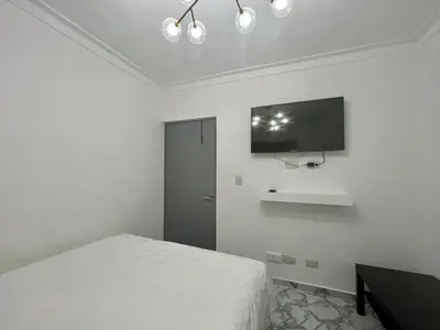 a white bedroom with a bed and a flat screen tv at Acogedor apartamento 2 hab Distrito nacional, próximo agora mall in Santo Domingo