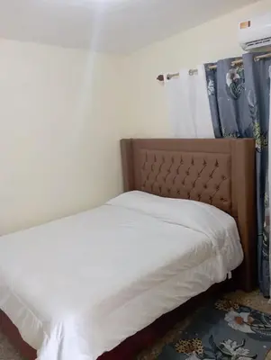 a bedroom with a bed with white sheets and a headboard at Lugar encantador en el Malecón Paraíso, Barahona. in Paraíso