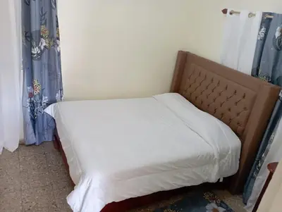 a bed with white sheets and blue curtains in a room at Lugar encantador en el Malecón Paraíso, Barahona. in Paraíso