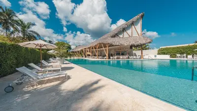 a swimming pool with chairs and umbrellas next to a resort at Beautiful 2 BR apartment at Portillo in Las Terrenas