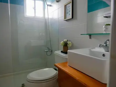 a white bathroom with a toilet and a sink at Lovely condo at Blue Sea Tower near Juan Dolio beach in Juan Pedro