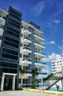 a tall building with palm trees in front of it at Lovely condo at Blue Sea Tower near Juan Dolio beach in Juan Pedro