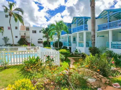 a house with a white fence and palm trees at B&B Aparthotel La Isleta in Las Galeras
