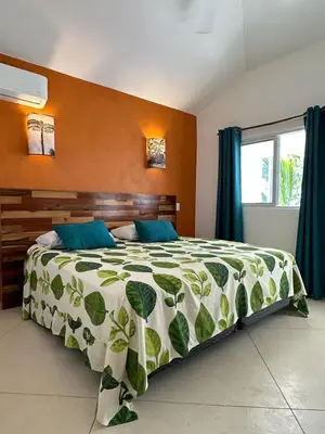 a bedroom with a bed with a green and white comforter at Hotel Casa Coson in Las Terrenas