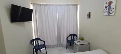 a bedroom with two chairs and a bed and a television at HEA Stays in San Felipe de Puerto Plata