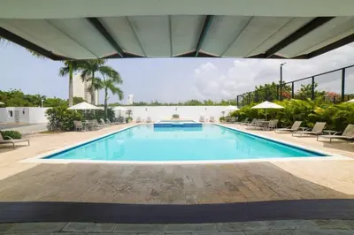 a large swimming pool with chairs and umbrellas at Elegant Blue Sky View Lux at Juan Dolio Las Velas in Juan Pedro