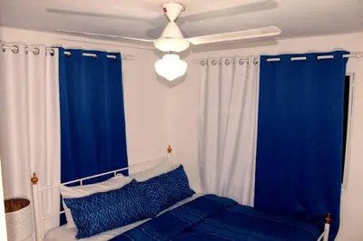 a bedroom with blue and white curtains and a ceiling fan at Dominican Suite 12, Incredible 2 Bed Apt (DS12) in San Felipe de Puerto Plata