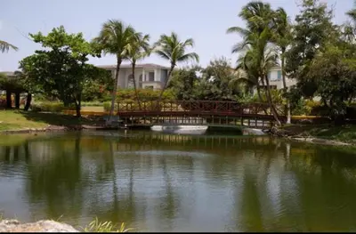 a bridge over a pond in front of a house at Luxury apto 3 rooms+pool+ campo de golf. Cocotal in Punta Cana