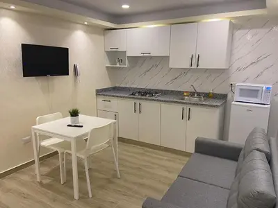 a living room with a table and a kitchen at Studios Don Bosco in Santo Domingo