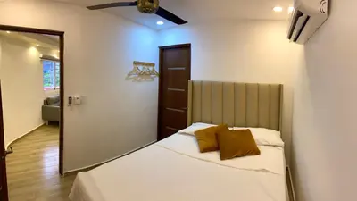 a bedroom with a bed with white sheets and brown pillows at Studios Don Bosco in Santo Domingo