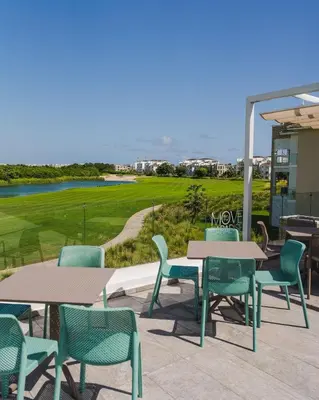 a patio with tables and chairs and a golf course at Pool & Golf View Condo Inside Hard Rock Area in Punta Cana