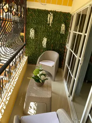 a balcony with a green wall with a table and chairs at VIP Home in Santiago de los Caballeros