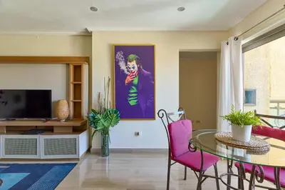 a living room with a table and a painting of the joker at VIP Exclusive One Bedroom Apartment in Santo Domingo