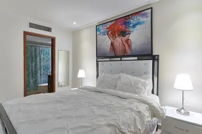 a bedroom with a white bed with a large painting on the wall at VIP Exclusive One Bedroom Apartment in Santo Domingo