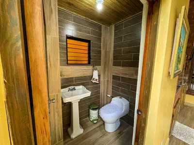 a small bathroom with a toilet and a sink at Villa Rosalía Jarabacoa con Piscina Climatizada in Jarabacoa