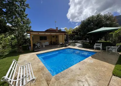 a swimming pool with two chairs and a house at Villa Rosalía Jarabacoa con Piscina Climatizada in Jarabacoa