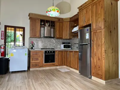 a kitchen with wooden cabinets and a refrigerator at Villa Rosalía Jarabacoa con Piscina Climatizada in Jarabacoa