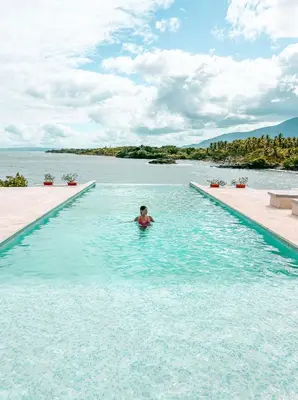 a person in a swimming pool in a body of water at Peninsula Esmeralda Luxury Hotel & Villas in San Felipe de Puerto Plata