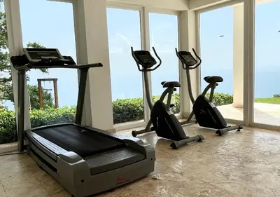 a gym with treadmills and ellipticals in a room with windows at Lovely house with private beach in Santa Bárbara de Samaná