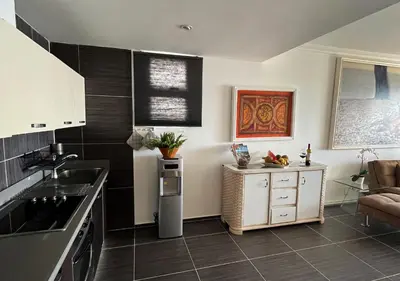 a kitchen with white cabinets and black tile floors at Lovely house with private beach in Santa Bárbara de Samaná