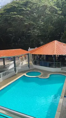 a large blue swimming pool next to a building with an orange roof at El Paso Hotel in Arroyo de Agua