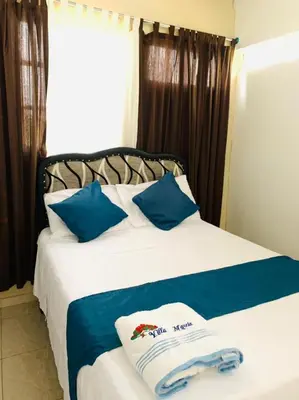 a bedroom with a bed with blue and white pillows at Villa Marcia in Boca Chica