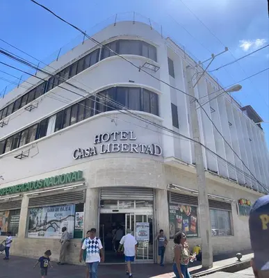 a building with people walking in front of it at Hotel Libertad at historic main street in Santo Domingo