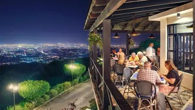 a group of people sitting at tables on a balcony at night at Las vacaciones que soñaste en un lugar seguro! in Santiago de los Caballeros