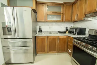 a kitchen with wooden cabinets and a stainless steel refrigerator at Las vacaciones que soñaste en un lugar seguro! in Santiago de los Caballeros