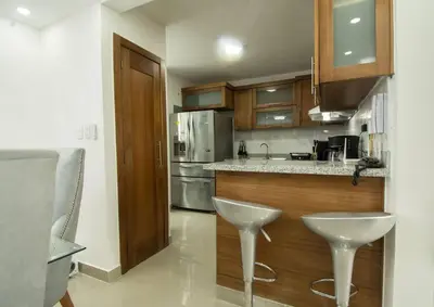 a kitchen with a counter and two white stools at Las vacaciones que soñaste en un lugar seguro! in Santiago de los Caballeros