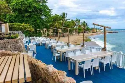a row of tables and chairs on a beach at Cerca del Mar, Obelisco Macho y Zona Colonial in Santo Domingo