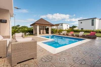 a swimming pool with chairs and a gazebo at The Green Palms 5 Bedroom villa with pool / garden in San Felipe de Puerto Plata