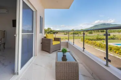 a balcony with a chair and a table and a view at The Green Palms 5 Bedroom villa with pool / garden in San Felipe de Puerto Plata