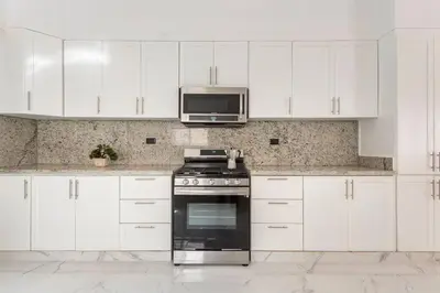 a kitchen with white cabinets and a stove and a microwave at The Green Palms 5 Bedroom villa with pool / garden in San Felipe de Puerto Plata