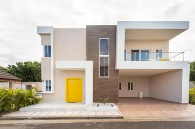 a modern house with a yellow door at The Green Palms 5 Bedroom villa with pool / garden in San Felipe de Puerto Plata