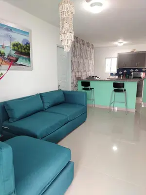 a living room with a blue couch and a kitchen at Mi refugio cerca del aeropuerto in Santo Domingo