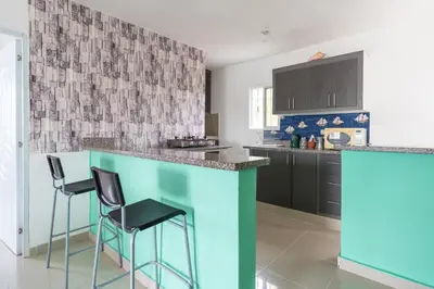 a kitchen with a blue counter and two stools at Mi refugio cerca del aeropuerto in Santo Domingo