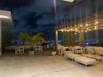 a rooftop patio at night with chairs and tables at Piantini’s Skylight in Santo Domingo